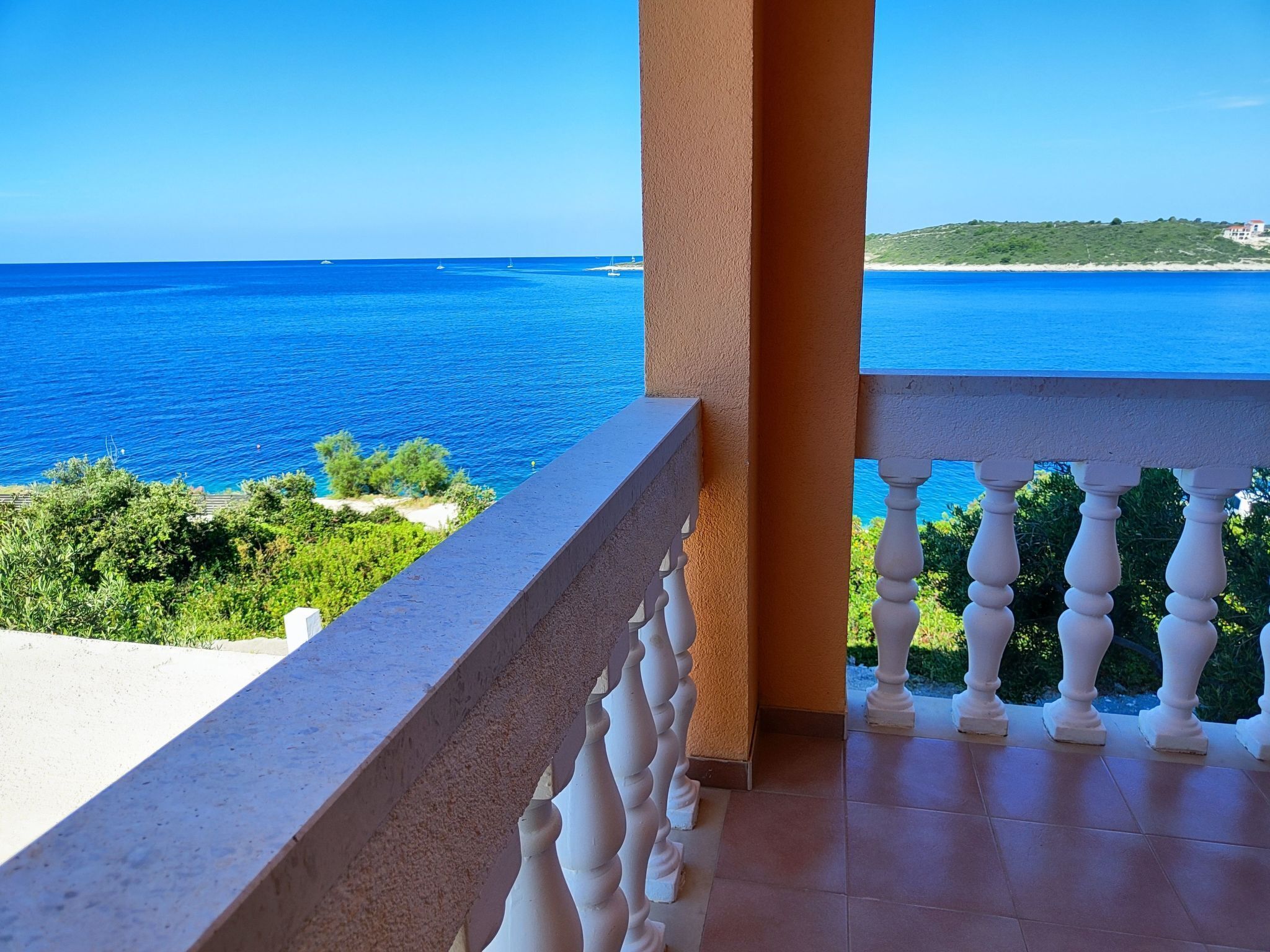 A balcony with a view of the sea and greenery.