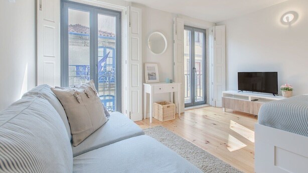 A modern living room with a sofa, TV, and a desk with a computer. - Downtown Porto Flat, Walk to City Center (Porto)