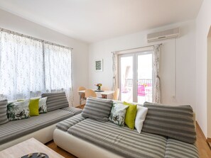 Ein modernes Wohnzimmer mit einer Sofagarnitur, einem Essbereich und einem Balkon.