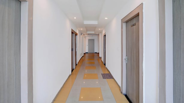 A corridor with doors on both sides, a tiled floor, and recessed ceiling lighting. - Shahpura Lakeview (Bhopal)