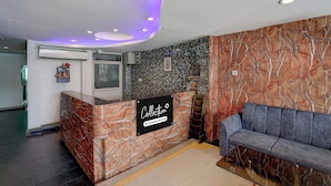 A reception area with a marble counter, a sofa, and a wall with a stone pattern. - Shahpura Lakeview (Bhopal)