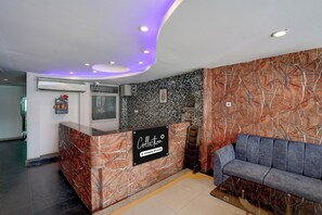 Un espace d’accueil doté d’un comptoir en marbre, d’un canapé et d’un mur au motif de pierres.