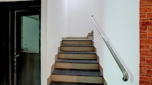 A staircase with a metal handrail, a door with a glass panel, and a brick wall. - Shahpura Lakeview (Bhopal)