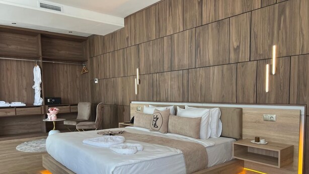 A modern bedroom with a large bed, bedside tables, a wardrobe, and a seating area. - Dar Zaha (Ksar es Seghir)