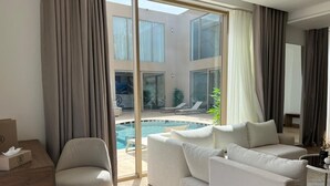 A modern living room with a pool view, a sofa set, and a wooden table with a box. - Dar Zaha (Ksar es Seghir)
