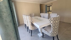 Un comedor con una mesa blanca y sillas estampadas.