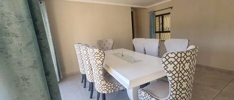 Un comedor con una mesa blanca y sillas estampadas.