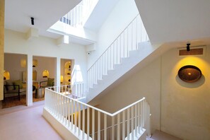 Ein modernes Interieur mit einer Treppe, weißen Geländern und einem Essbereich mit Tischen und Stühlen.