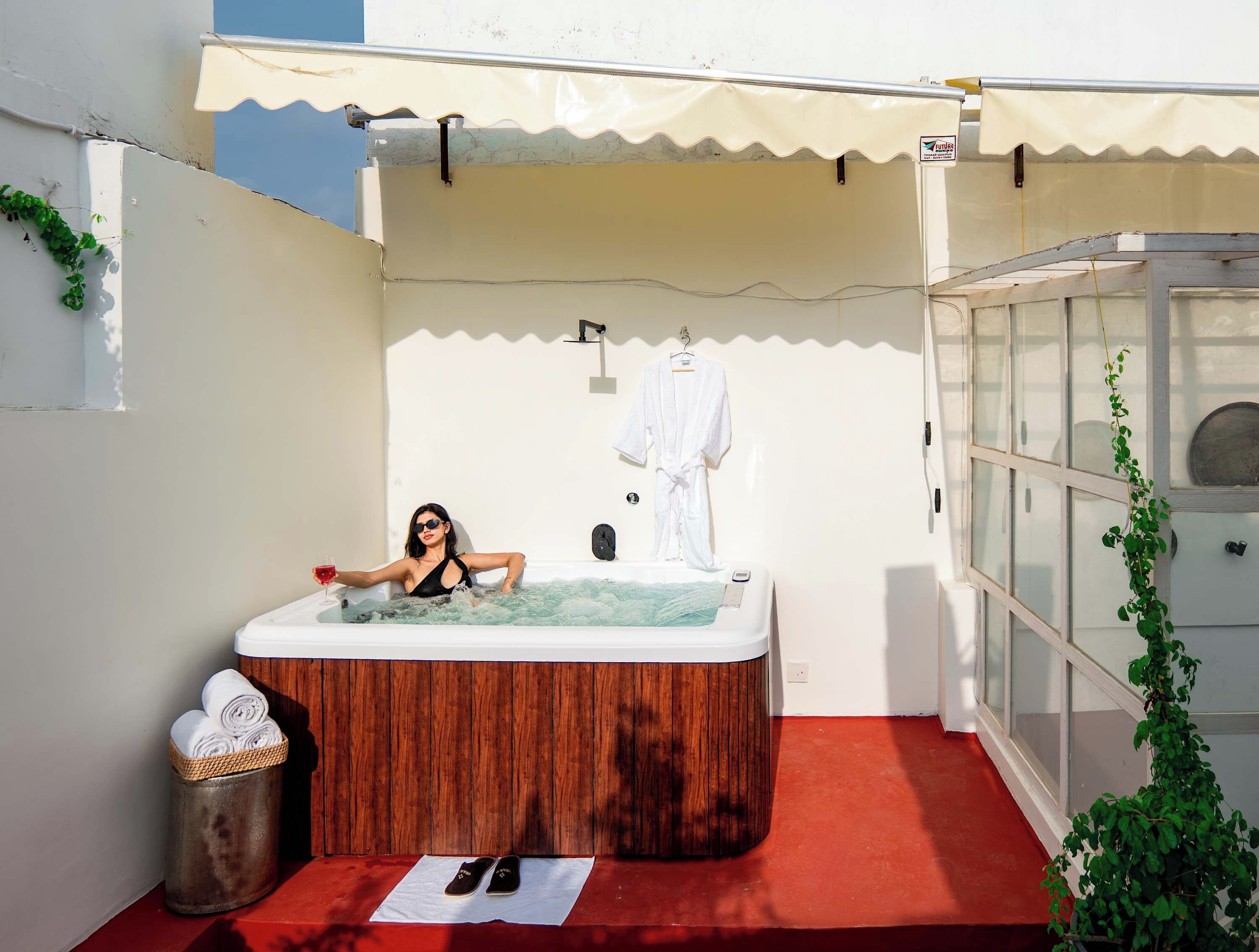 A spa area with a hot tub, a wooden bench, and a towel rack.