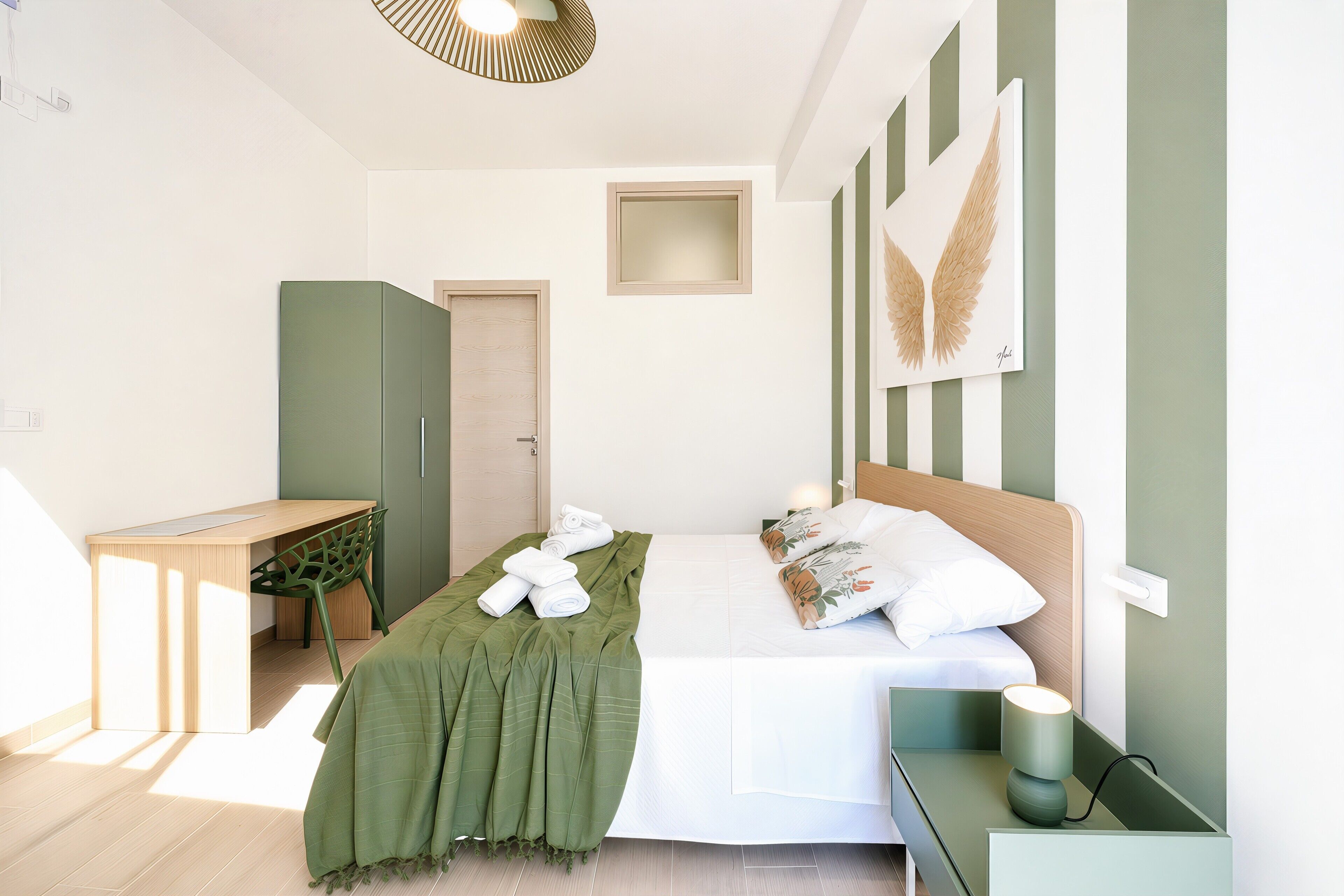 A modern bedroom with a bed, bedside table, and a desk with a chair.