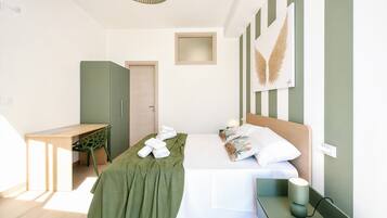 A modern bedroom with a bed, bedside table, and a desk with a chair.