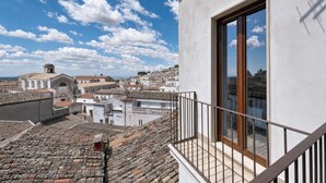 Une terrasse sur le toit offrant une vue sur une ville historique, une balustrade en bois et un ciel dégagé.