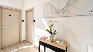 Un couloir avec des portes en bois, un bureau orné d’un vase de fleurs et une œuvre d’art accrochée au mur.