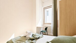 Una habitación de hotel con cama, una silla, un escritorio y una ventana con cortinas.