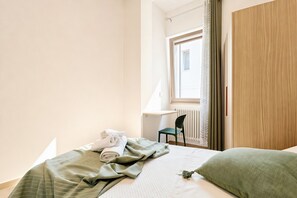Een hotelkamer met een bed, een stoel, een bureau en een raam met gordijnen.