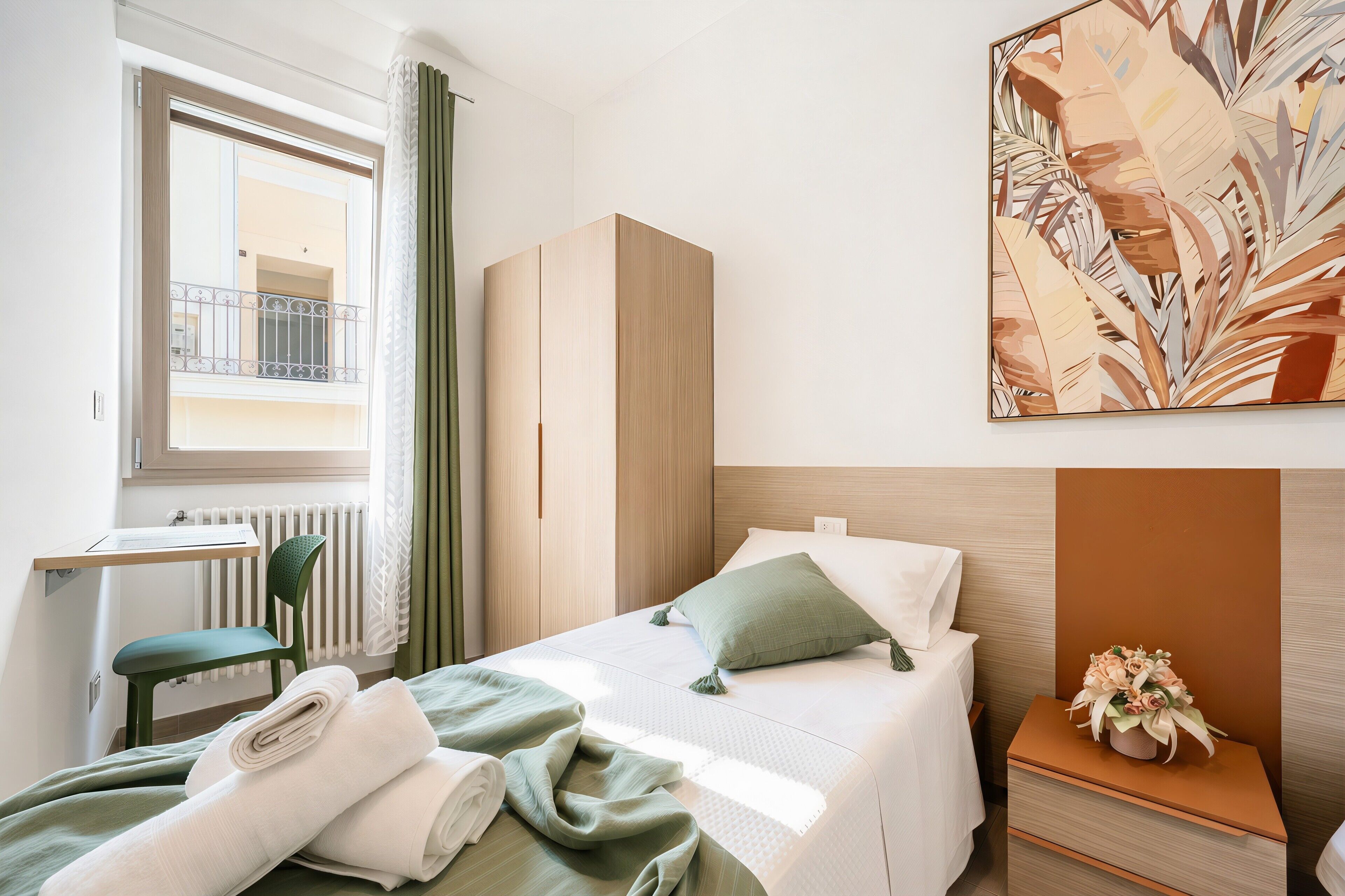 Une chambre d’hôtel avec un lit, un bureau, une chaise, une armoire et un tableau au mur.