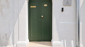 A green double door with a brass handle and a plaque, set in a white building with a small step leading up to it. - ‘Domus Dell’Angelo 4’ – Comfort and Authenticity in the Heart of Monte Sant’Angelo (Monte Sant'Angelo)