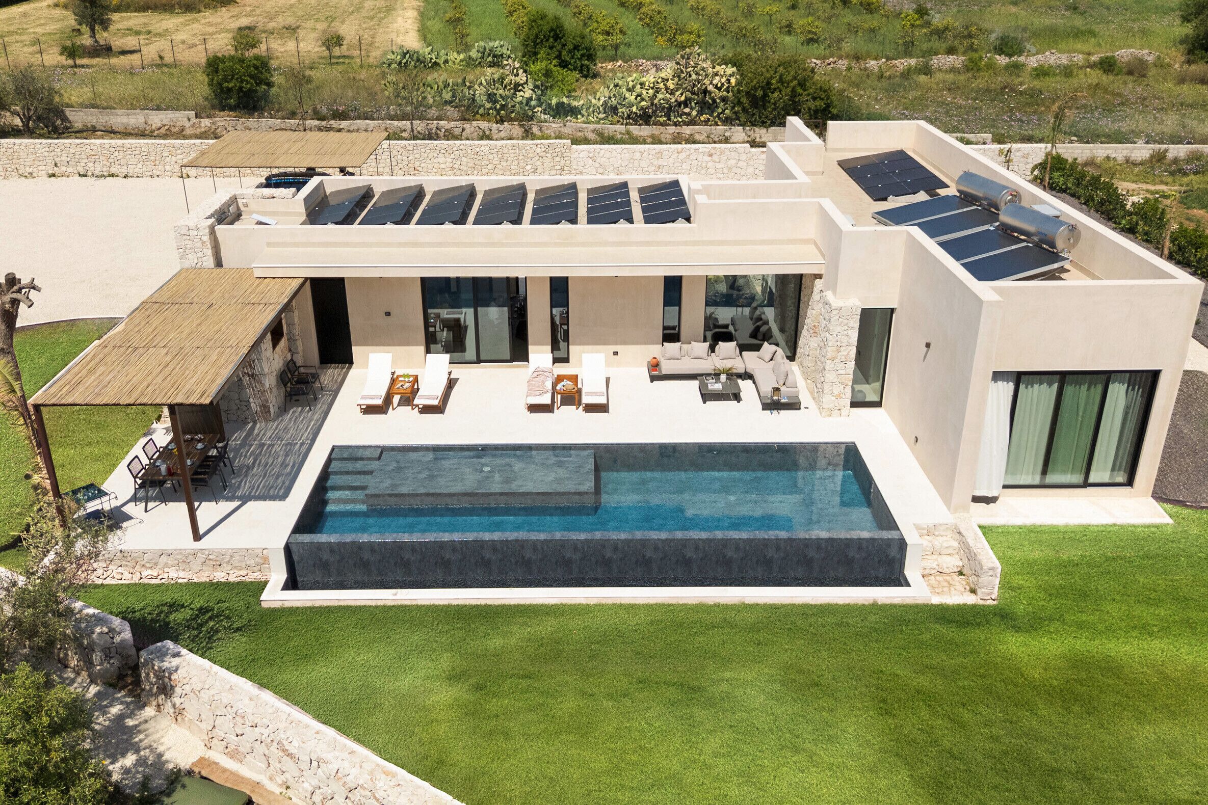 Een modern huis met een zwembad, zonnepanelen en terras.
