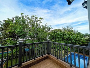 A balcony with a wooden floor and metal railing overlooking a swimming pool and lush greenery. - Lavia Villas & Apartment Phu Quoc (Phu Quoc)