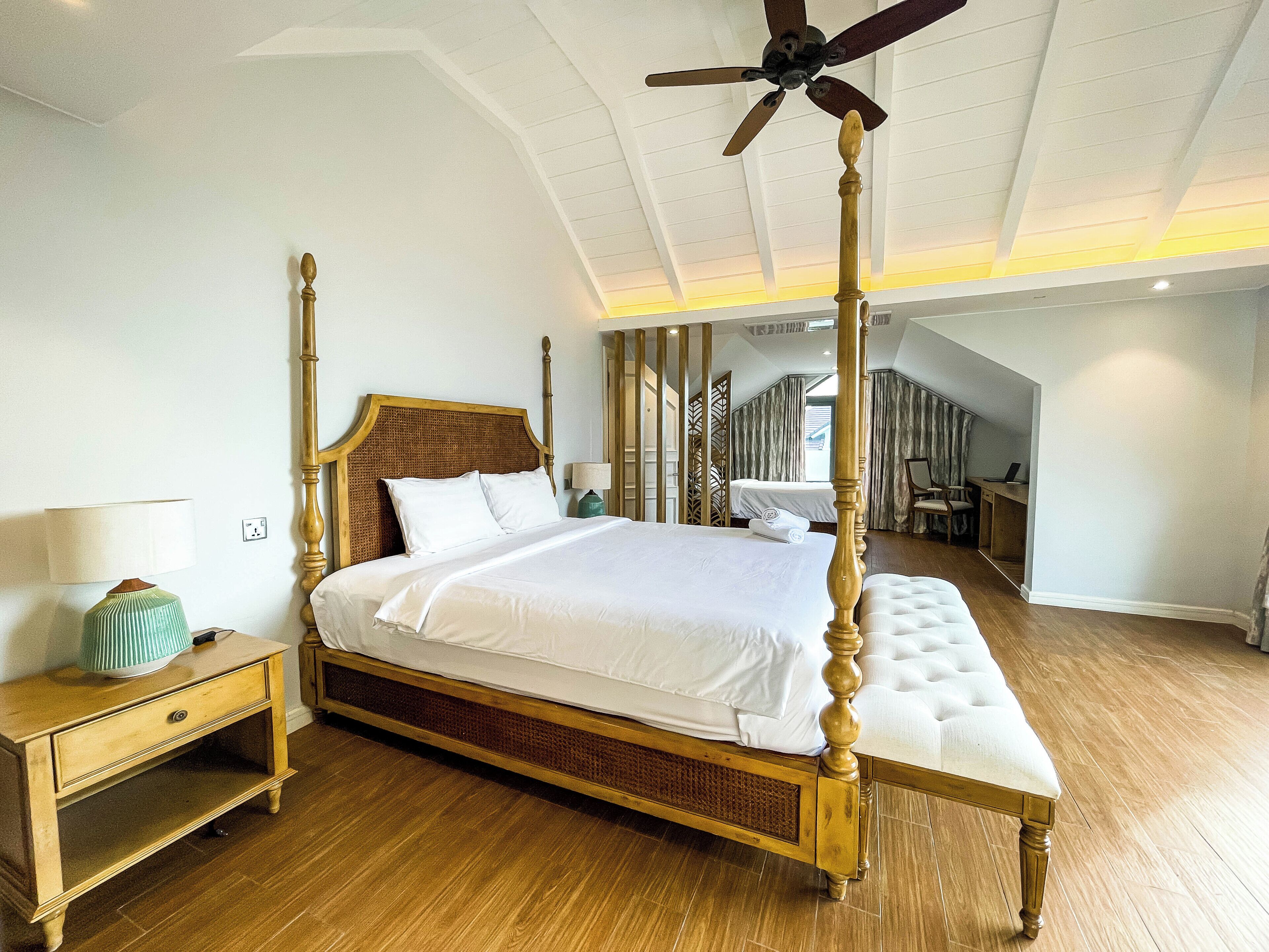 Una cama con dosel y estructura de madera, con un ventilador de techo.