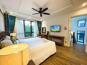 Habitación de hotel con cama, escritorio, televisor y vistas al exterior.
