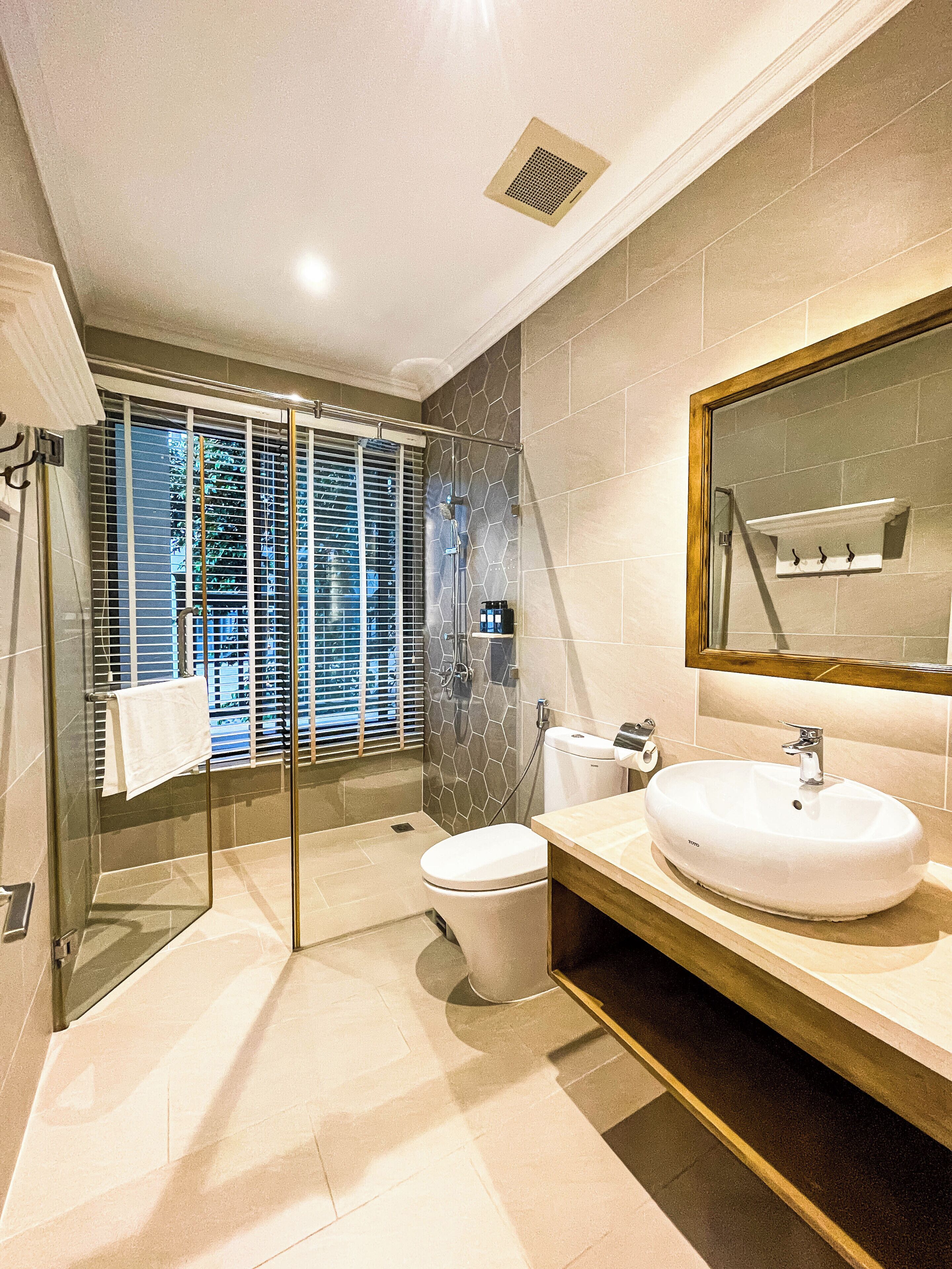 Un baño moderno con ducha de vidrio, inodoro y lavamanos con espejo.