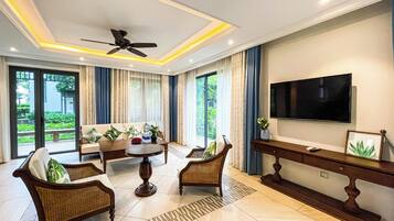 A modern living room with a ceiling fan, a flat-screen TV, and a sofa set.