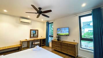 A hotel room with a bed, a desk, a television, and a window with curtains.