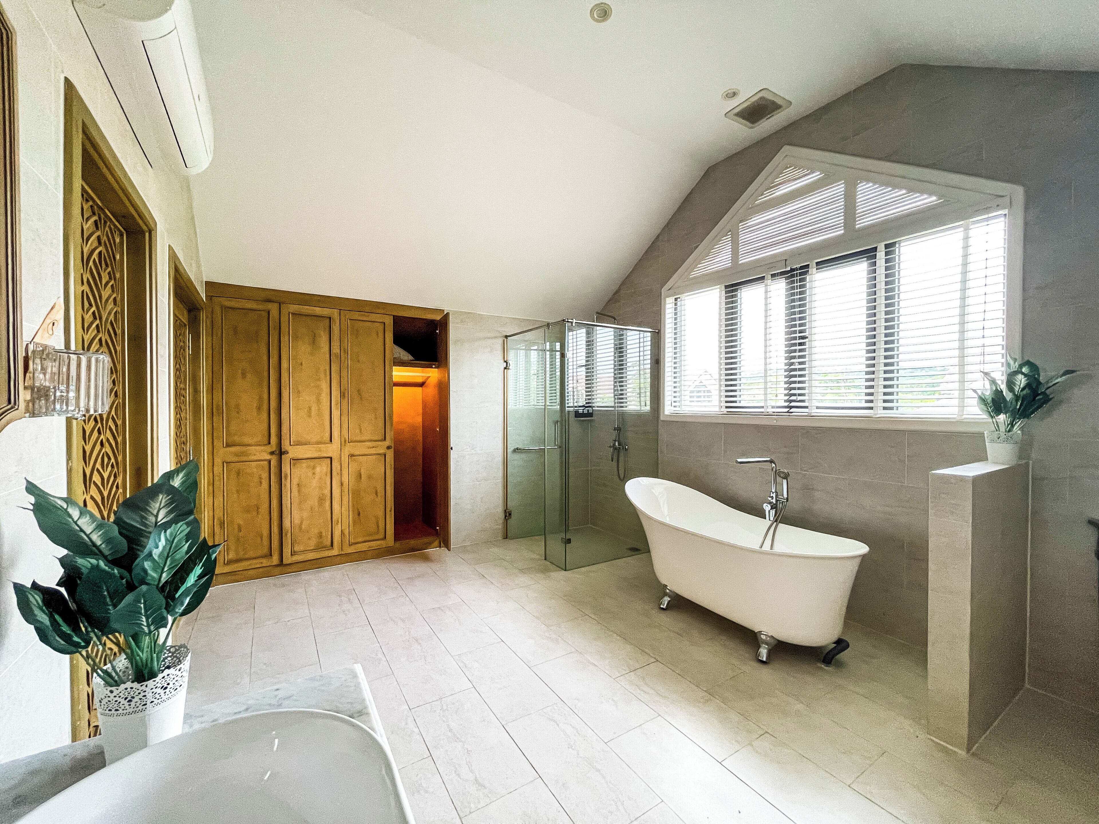A bathroom with a freestanding bathtub, a glass shower enclosure, and a wooden wardrobe.