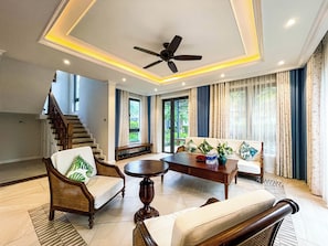 A spacious living area with a ceiling fan, a sofa set, a dining table, and a staircase leading to an upper floor. - Lavia Villas & Apartment Phu Quoc (Phu Quoc)