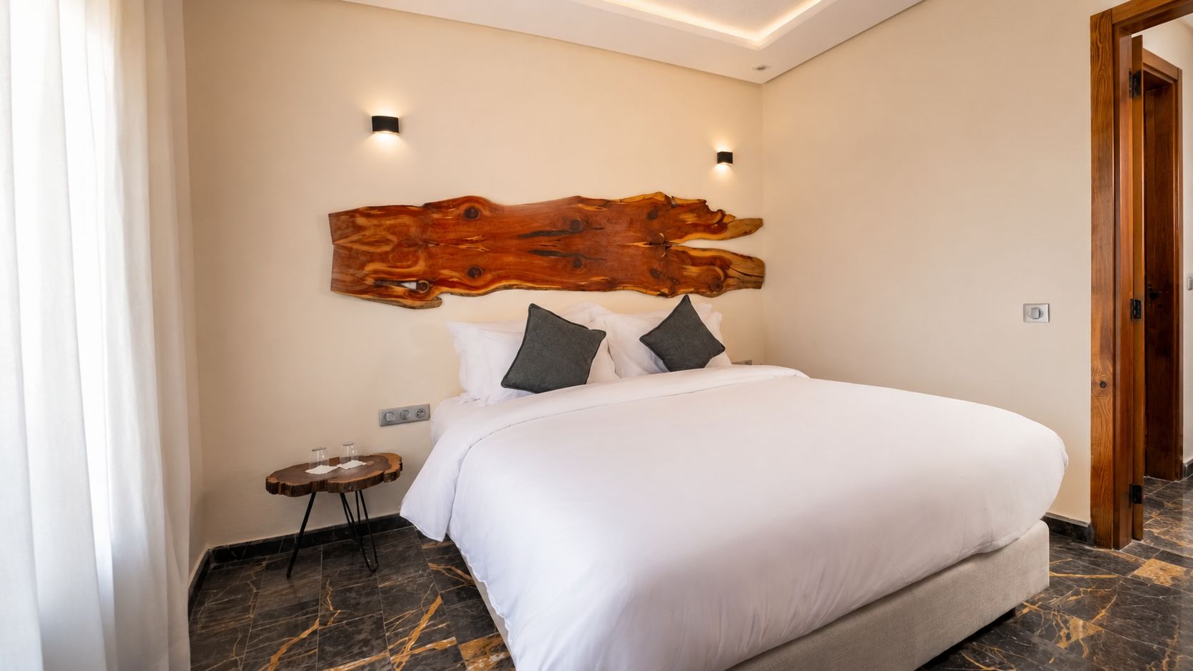 A hotel room with a large bed, a wooden headboard, a small bedside table, and a nightstand.