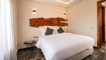 A hotel room with a large bed, a wooden headboard, a small bedside table, and a nightstand.