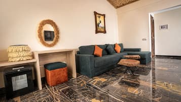 Una sala de estar moderna con un sofá, un reposapiés y una mesa de centro, una chimenea y un cuadro en la pared.