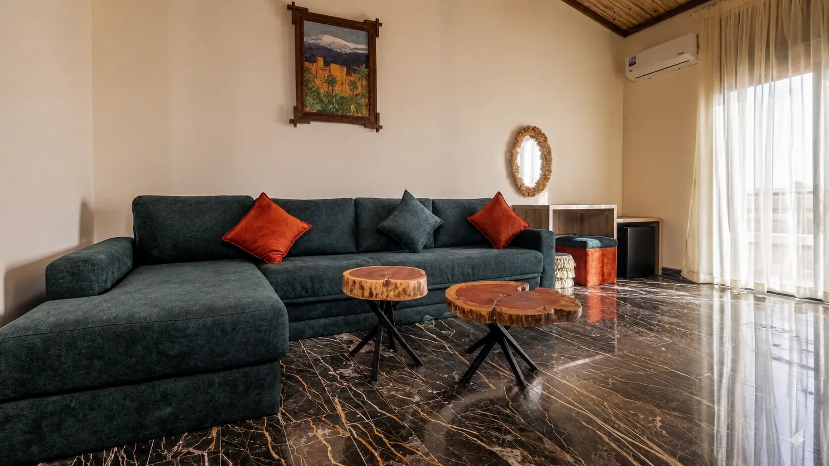 Ein modernes Wohnzimmer mit einem Ecksofa, zwei runden Holztischen, einem Gemälde, einem Spiegel und einer kleinen Kommode.