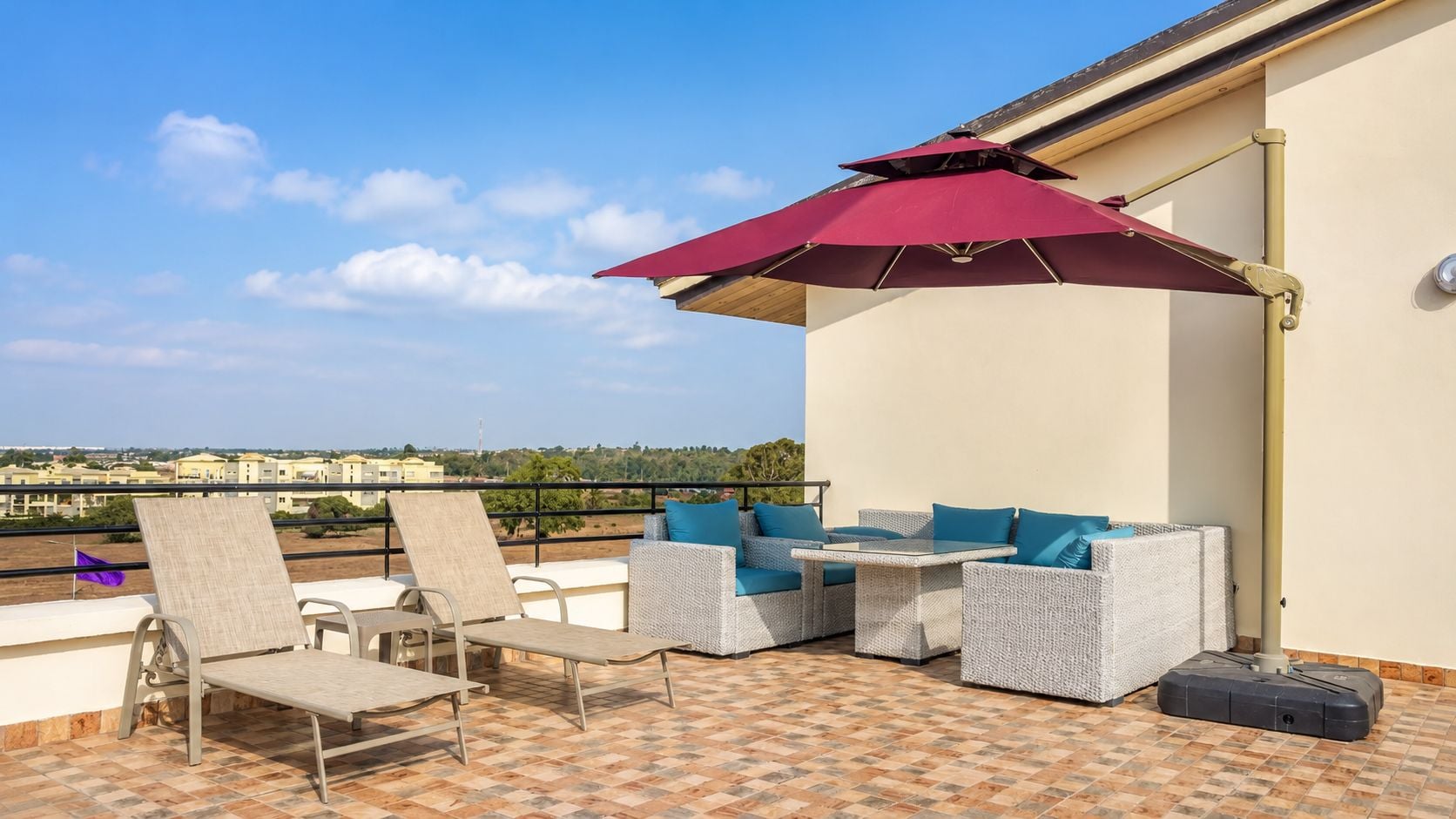 A terrace with outdoor furniture, a table, and a red umbrella.