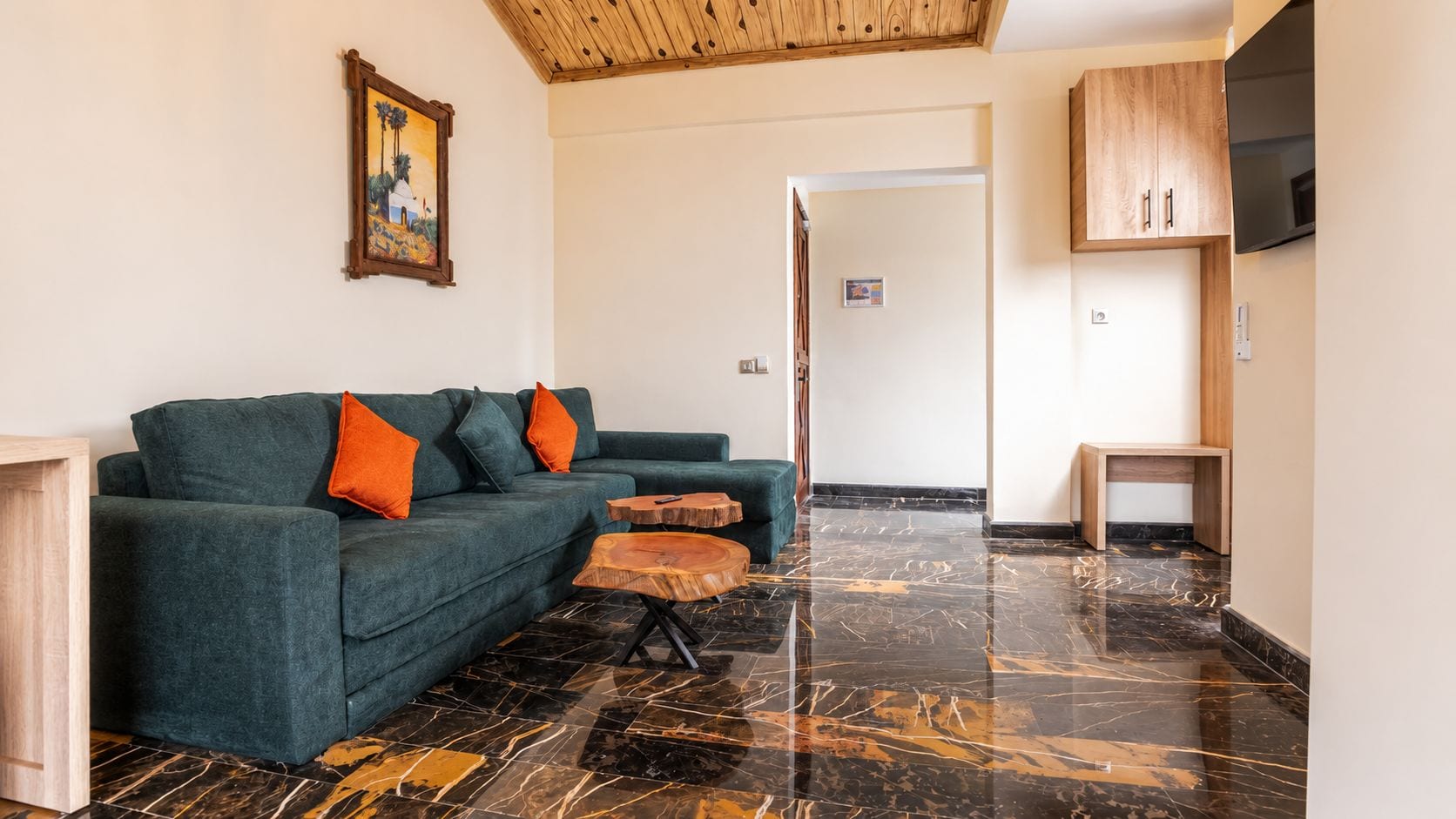 Una sala de estar con un sofá, dos mesitas auxiliares y un televisor.