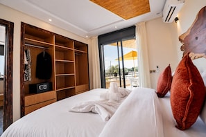 A hotel room with a large bed, a wooden wardrobe, a balcony with a yellow umbrella, and a large wooden headboard. - Hotel Paradise KMA (Cherrat)