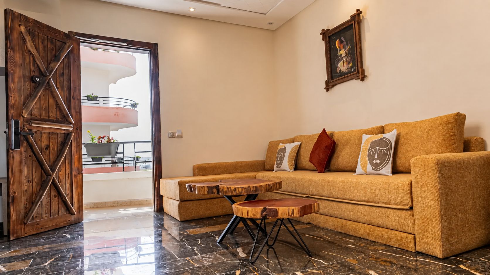 Uma sala de estar com porta de madeira, sofá com almofadas, mesa de centro e um quadro na parede.