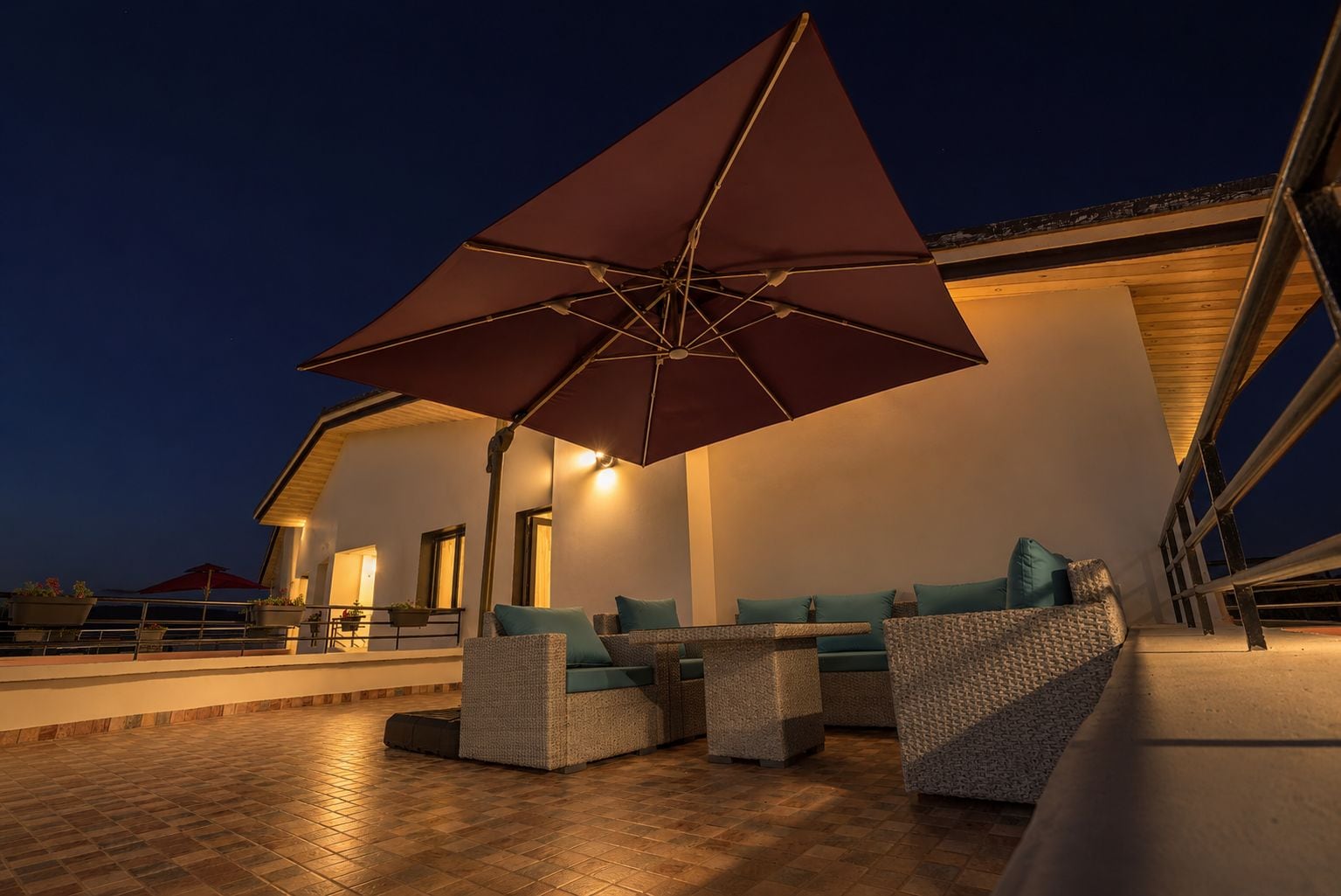 An outdoor seating area with a large umbrella, wicker furniture, and a view of a building.