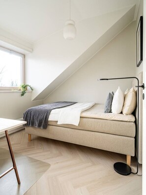 A compact, modern bedroom with a loft-style bed, a small table, and a window with a view. - Contemporary penthouse with balcony (Tallinn)