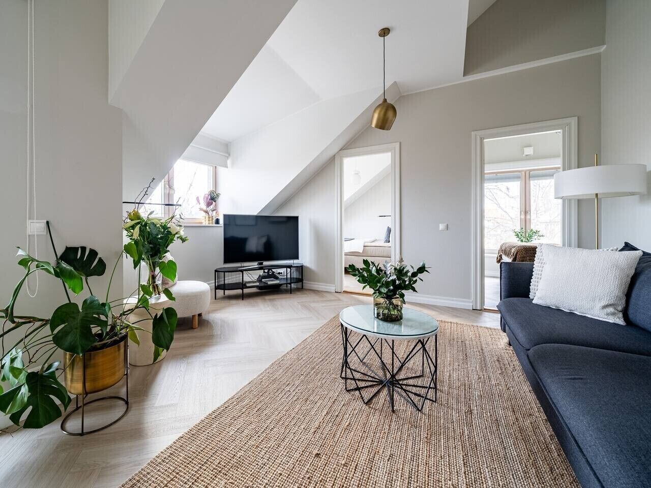 A modern living room with a flat-screen TV, a dark sofa, and a round coffee table.