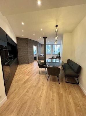 Eine moderne Küche mit Einbauofen, einem Essbereich mit rundem Tisch und Stühlen sowie Blick ins Freie durch große Fenster.