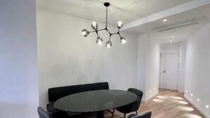 A modern dining area with a round table and four chairs, a unique chandelier, and wooden flooring. - Spacious, recently renovated loft with air conditioning (Île-de-France)