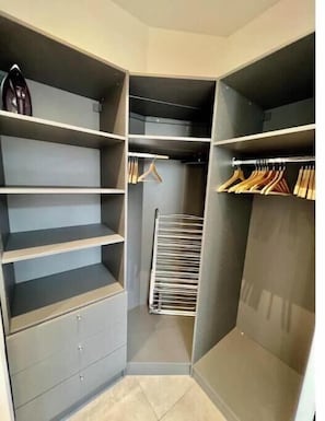 Ein begehbarer Kleiderschrank mit mehreren Regalen, Kleiderstangen und einem Schuhregal.