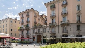 Um edifício histórico com varandas elaboradas e um café no térreo com mesas ao ar livre.