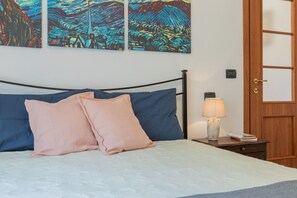 A bedroom with a bed, pillows, a bedside table with a lamp, and wall art. - Finestra sulle Porte Palatine by Wonderful Italy (Turin)