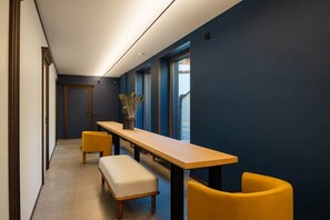 A hallway with a long wooden table, yellow chairs, and a bench.