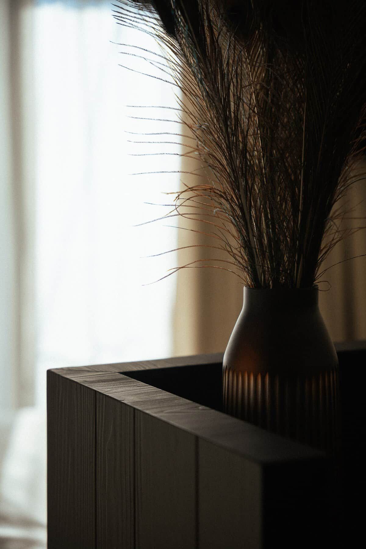 A dark wooden cabinet with a vase containing dried plants.