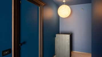 A hallway with a blue wall, a wooden door, and a light fixture.