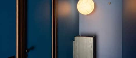 A hallway with a blue wall, a wooden door, and a light fixture.